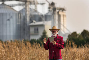 Canvas Print - Farmer with tablet in front of grain silos