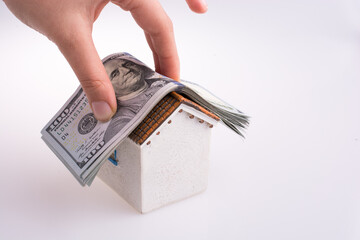 Wall Mural - Hand holding American dollar banknotes on the roof of a model house