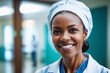 portrait shot of middle age african american female doctor in doctors outfit looking at camera while standing in the hospital, sly smile, blurred background