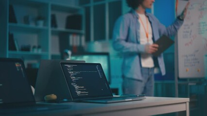 Male IT developer brainstorming with a colleague near whiteboard in an office
