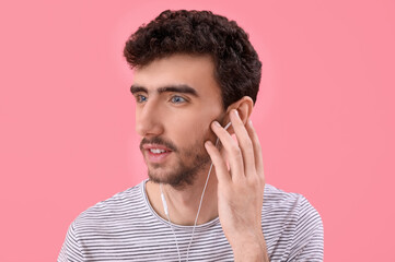 Poster - Young brunette man in earphones on pink background, closeup