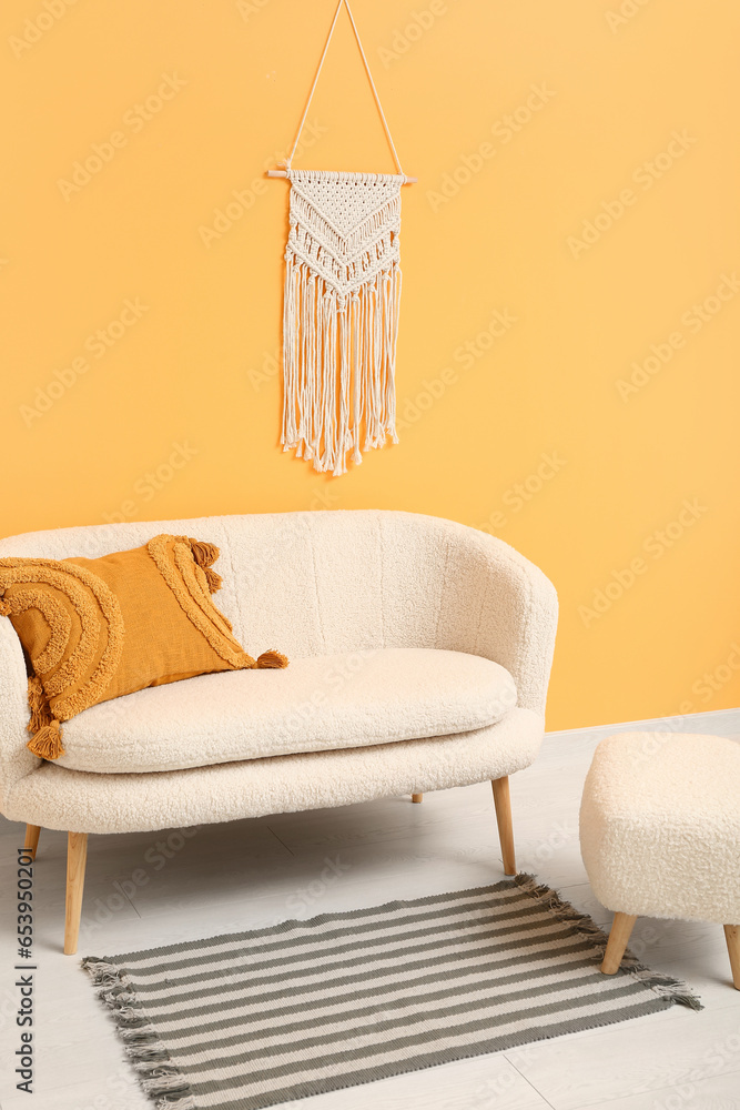 Cozy white sofa and ottoman near orange wall with wicker decor