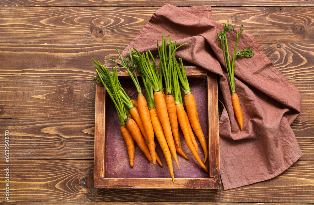 Tasty fresh carrot and board on wooden background