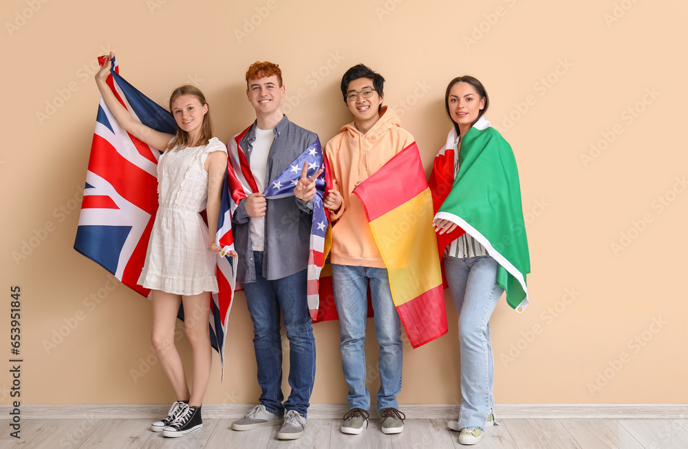 Young students of language school with flags near beige wall