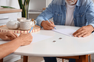 Canvas Print - Mature couple signing divorce decree in kitchen, closeup