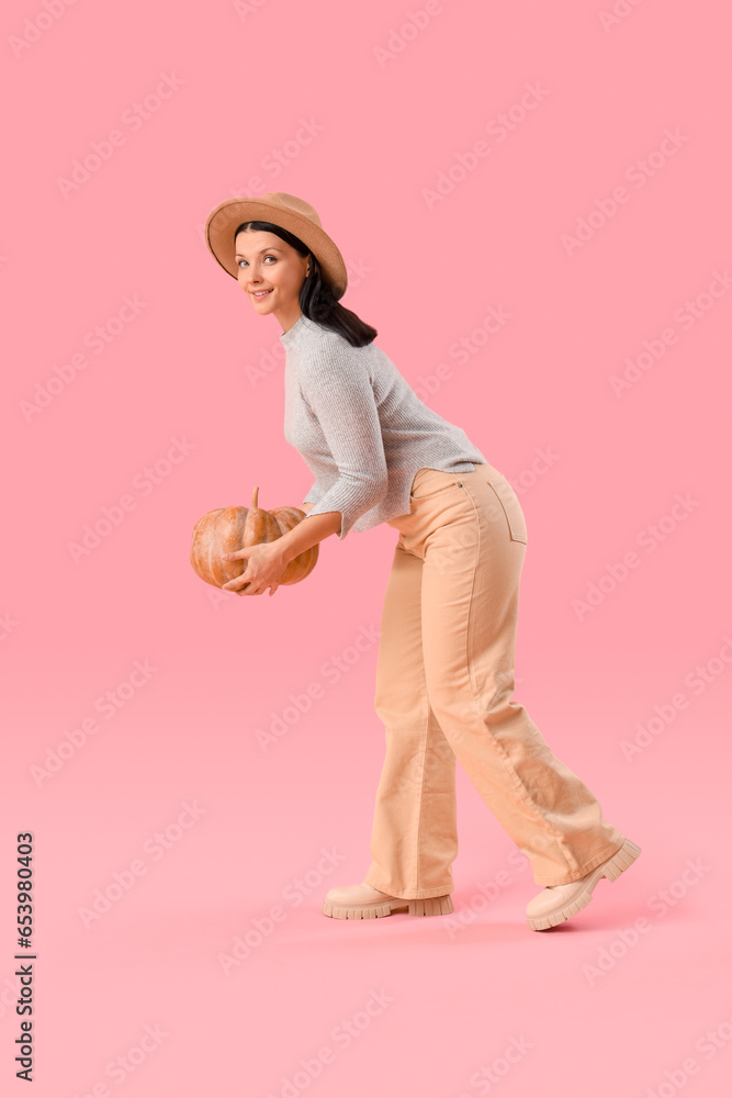 Beautiful woman with pumpkin on pink background
