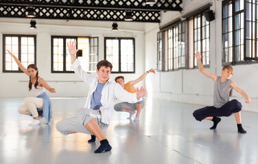 Wall Mural - One young lady and few boys dancing modern dance on rehearsal