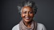 Mature Afro-American woman with grey hair smiling against a neutral background, exuding confidence.