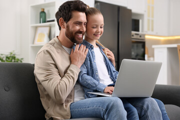 Canvas Print - Happy man and his daughter with laptop on sofa at home