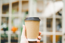 A Man's Hand Holding A Cup Of Coffee In The Morning With Red Brick Background. Concepts Of Lifestyle Coffee Shop Is The Perfect Place To Meet Family Or Friends For A Relaxing Breakfast.