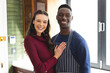 Portrait of happy diverse couple embracing and smiling in kitchen at home