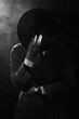 a dark silhouette of a man in a raincoat and a hat in the style of crime noir. Dramatic noir portrait in the style of detectives of the 1950s. There is smoke in the photo