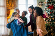 © NDABCREATIVITY - Excited multiethnic family greeting grandparents on Christmas Day. Multi-generational happy family
