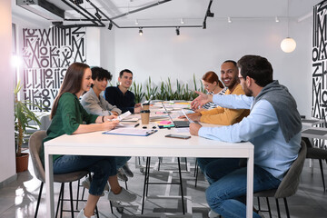 Canvas Print - Team of employees working together at table in office. Startup project