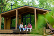 © Guys Who Shoot - a young family of a man and a woman rejoicing over the purchase of their own wooden house in forest