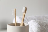 Fototapeta Sypialnia - Holder with bamboo toothbrushes on blurred background, closeup. Space for text