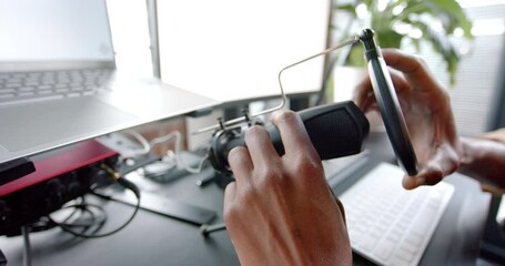 Wall Mural - happy african american man setting up microphone for live podcast at home, slow motion