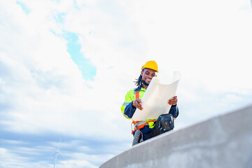 Wall Mural - Technician engineer African man worker builders looking for wind turbine blueprint drawings for wind turbine construction at windmill field farm. Alternative renewable energy for clean energy concept.