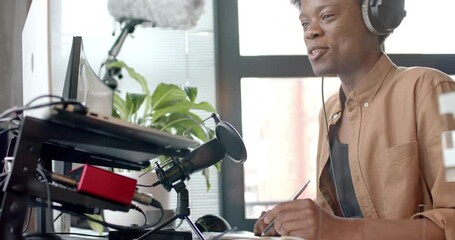 Wall Mural - happy african american man in headphones making live podcast from home, copy space, slow motion