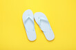 Leinwandbild Motiv Stylish white flip flops on yellow background, top view