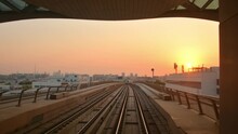 Dubai, UAE - 10th October, 2022: Metro Train On Railway Arrive To Station In Dubai City With Sunset Orange Sky Background