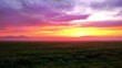 farbenfroher Sonnenaufgang über nebligen Wiesen mit Hügeln am Horizont mit violett orange farbenen Wolken
