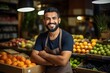 Smiling Middle Eastern male worker in a fruit shop with folded arms and looking at the camera