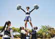 © Sharne/peopleimages.com - Teamwork, motivation or cheerleader in air with people outdoor in training routine or sports event. Jump, sky or girl by a happy cheer squad group on a field together for support, exercise or fitness