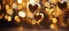 Festive Christmas Xmas Advent Valentine Celebration Concept Greeting Card - Golden Hanging Hearts On String With Gold Defocused Bokeh Lights In The Background