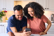 © Monkey Business - Couple At Home With Man With Down Syndrome Looking At Mobile Phone Together