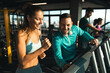 © Dorde - Young athlete male with headphones assisting a young woman while exercising on treadmills in a gym. Two people having engaging conversation during workout.