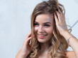 © Ulia Koltyrina - Charming cheerful blonde with long wavy hair and sparkling makeup. Beautiful young woman with sequins on her face