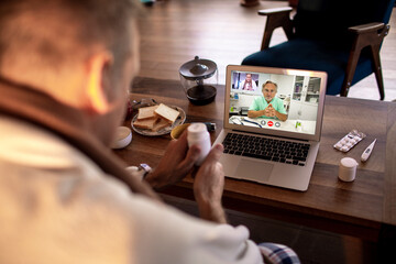 Middle aged man consulting his doctor on a video call about his medication at home