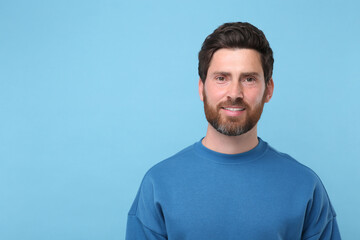 Poster - Portrait of handsome man on light blue background, space for text