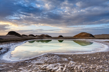 A Sulfur lake with sand rocks reflections in sunrise.