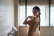 Nude Asian girl spray water to body. Nake woman bathing
