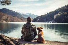 Rear View Of Man Traveler And His Dog Looking At Mountain Lake On Sunny Day