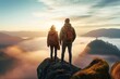 Rear view of young traveler couple with backpacks enjoying sunrise on misty mountain peak
