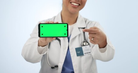 Canvas Print - Woman, doctor and phone with green screen in advertising against a studio background. Hands of female person, medical or healthcare surgeon pointing to mobile smartphone display, health app or mockup