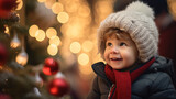 A smiling baby boy child at a Christmas market looking at christmas ornaments, christmas trees and lights, candles, white christmas snow happy holidays