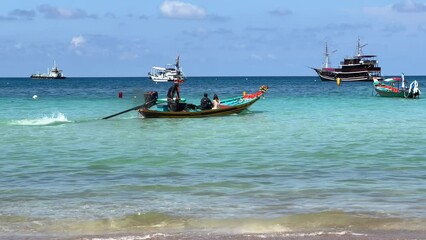 Wall Mural - The thai long-tail motor boat sails from the shore and goes out to sea in turquoise water. Tourists people use local water taxi transport on Sairee Beach