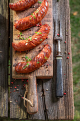 Wall Mural - Roasted sausages on wooden plate in garden.