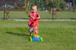 child mows the grass with a toy lawn mower