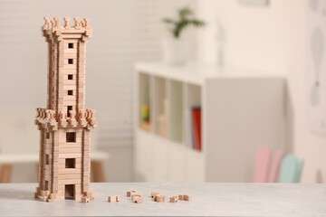 Canvas Print - Wooden tower on table indoors, closeup. Space for text. Children's toy