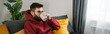 © satura_ - Young arab man drinking tea sitting on sofa at home copy space banner