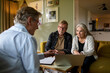 © Marko Geber - Senior Caucasian couple consulting their financial advisor at home
