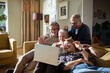 © Marko Geber - Group of senior friends having a video call with a friend on the couch at home