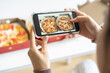 © KMPZZZ - Happy meal, enjoy eating beautiful asian young woman taking photo of pizza in box by mobile smart phone on table at home before eat fast or junk food, post picture to communication on social networks.