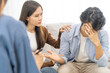 © KMPZZZ - Psychology, depression asian young couple love, woman, man patient consulting problem mental health with psychologist, psychiatrist at clinic together, wife encouraging husband,  therapy health care.