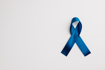 A shiny blue ribbon, symbolizing world diabetes day on November 14, stands out against a white background. Copy space for messages of support and care.